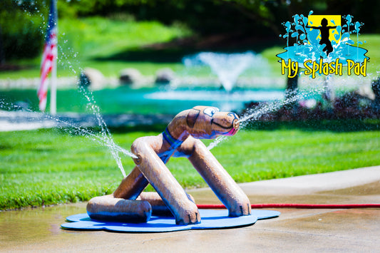 Sitting Dog Mobile Water Play Features by My portable splash pad. Trees and grass in the background. Sunny day in Ohio.
