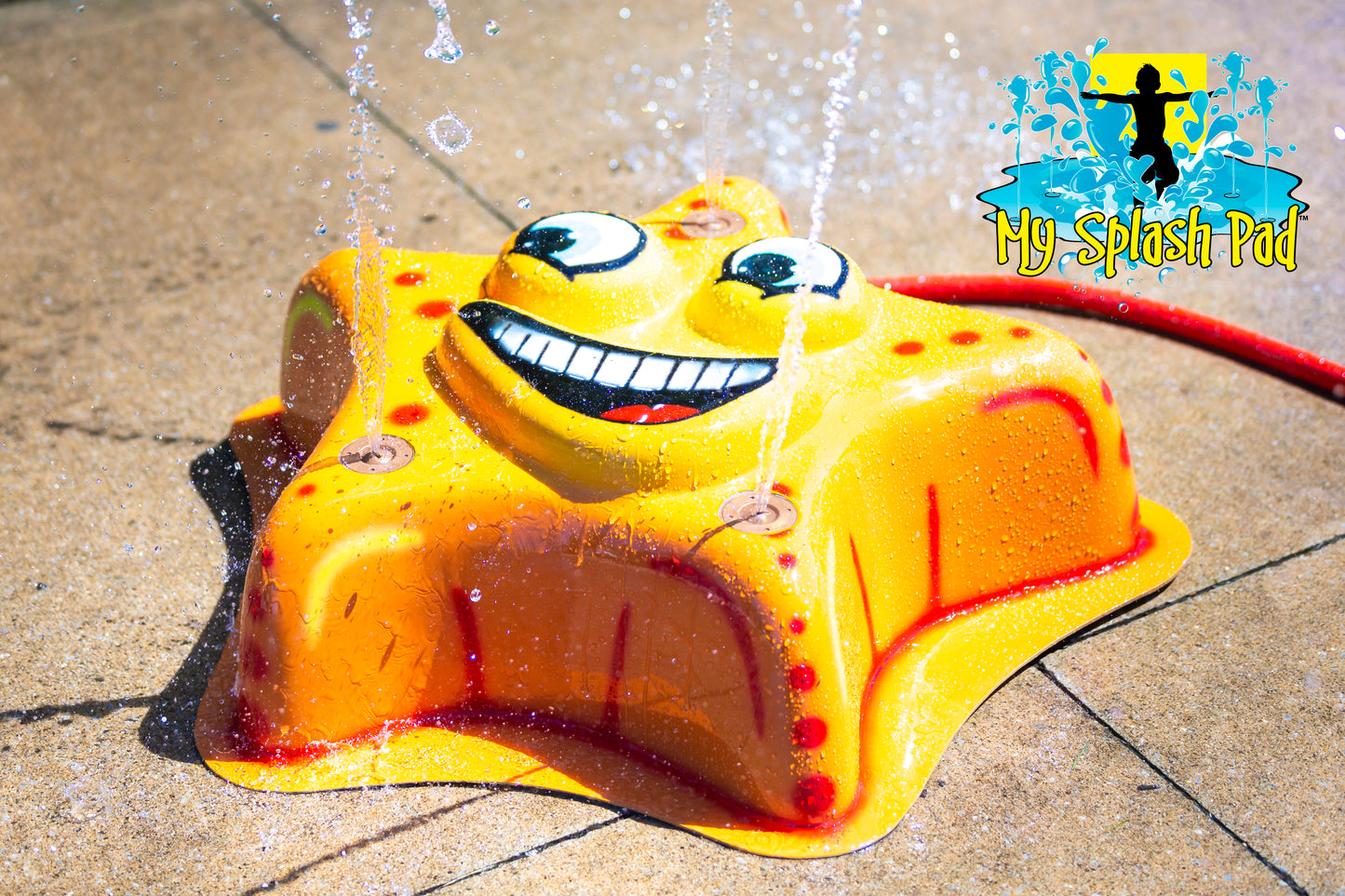Starfish Mobile Spray and Play Features – yellow starfish splash pad spraying water jets in a backyard play area.
