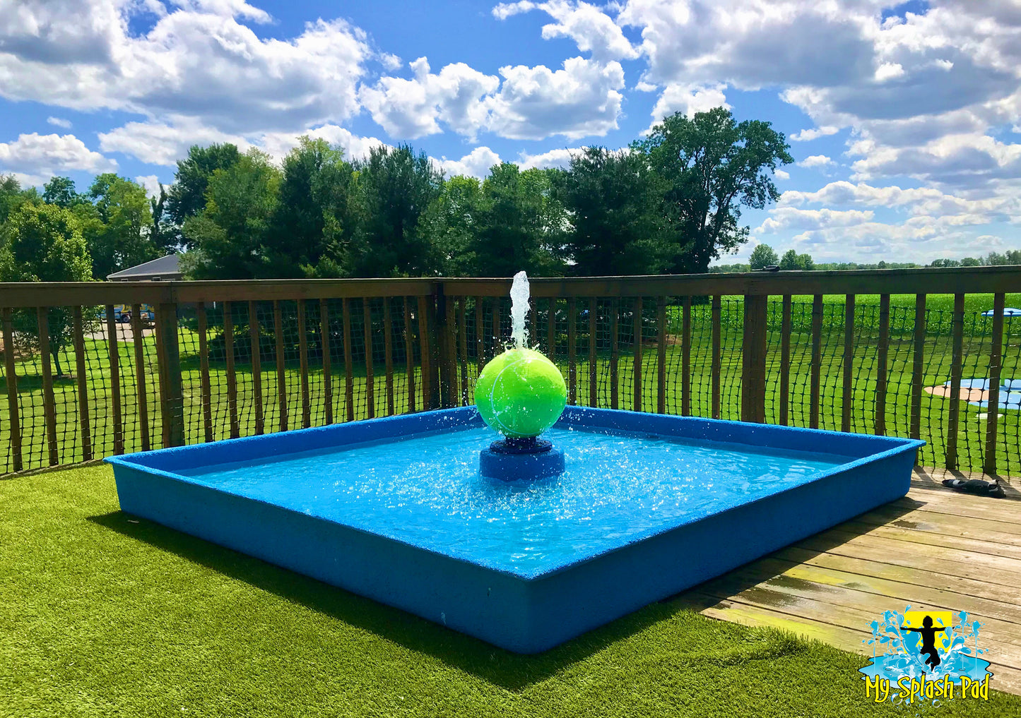 Tennis Ball Portable Water Play Feature by My Splash Pad installed in blue wading pool with green tennis ball sprayer on backyard deck.
