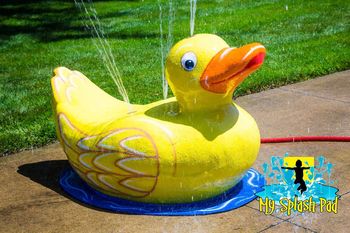 Duck Mobile Spray and Play Features – portable yellow duck splash pad with water jets spraying upward on concrete pad.