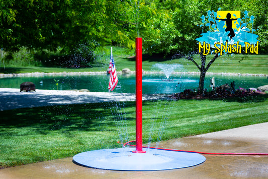 Tall red Rain Stick Splash Pad Water Play Feature spraying water streams from multiple nozzles, backyard pond setting.