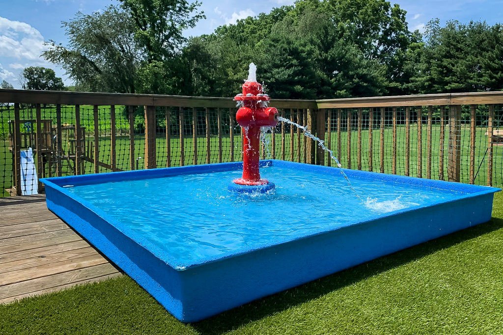 Dog Wading Pool by My Portable Splash Pad – blue rectangular pool with red fire hydrant water play feature spraying streams in backyard setting.