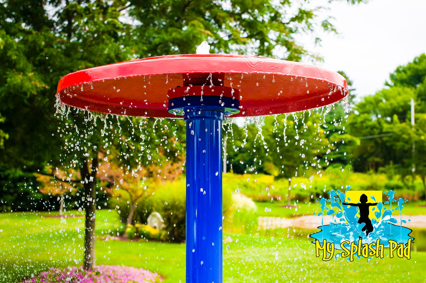Close-up of Umbrella Portable Splash Pad water play feature with red umbrella top and blue pole, spraying water streams outdoors.